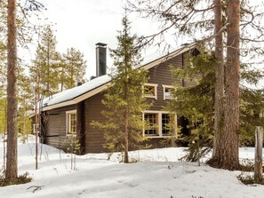 A wooden cabin surrounded by snow-covered ground and trees. - Susitupa 5 by Interhome (Salla)