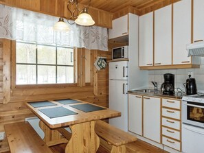 A wooden interior with a table and benches, a microwave, a coffee maker, and cabinets. - Susitupa 5 by Interhome (Salla)