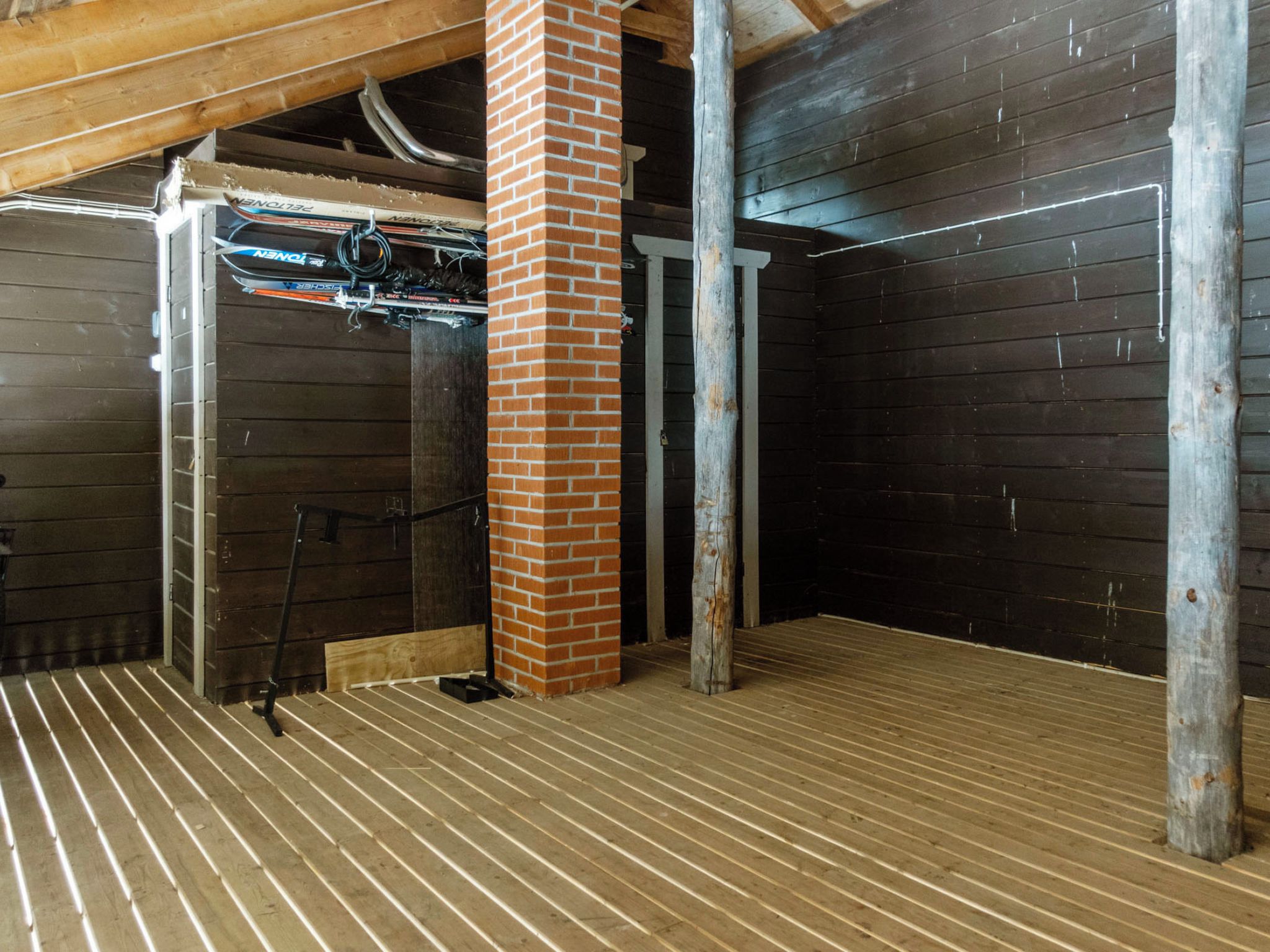 A room with a wooden floor, brick pillar, and metal beams.