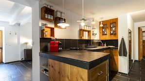 A modern kitchen with a central island, wooden cabinets, and built-in shelves with kitchen essentials. - Grangettes by Interhome (Noville)