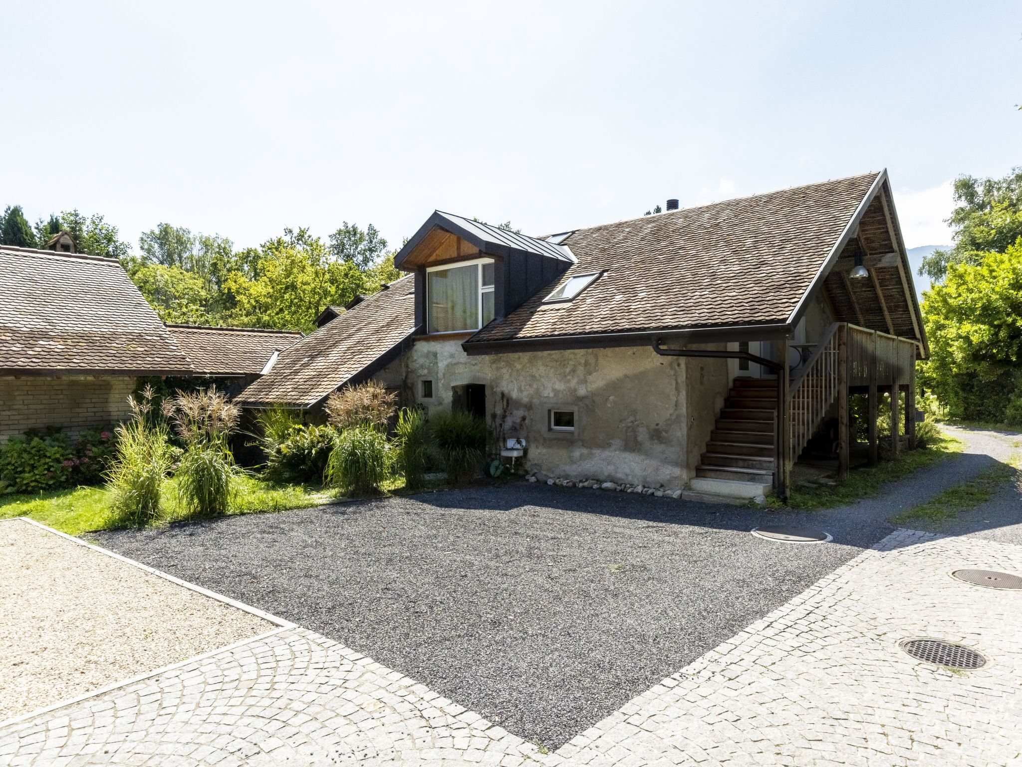 Un bâtiment rustique avec un toit en pente, une petite fenêtre et un escalier menant à une terrasse en bois.