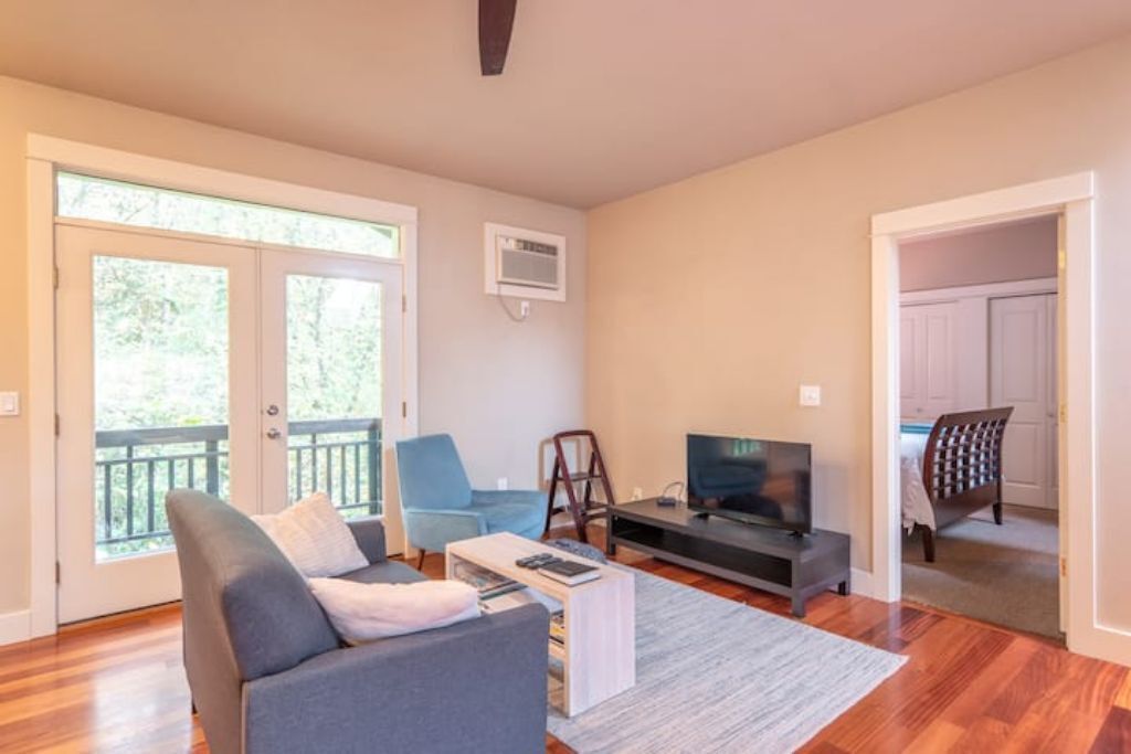 A living room with a sofa, a coffee table, a TV, and a balcony door.