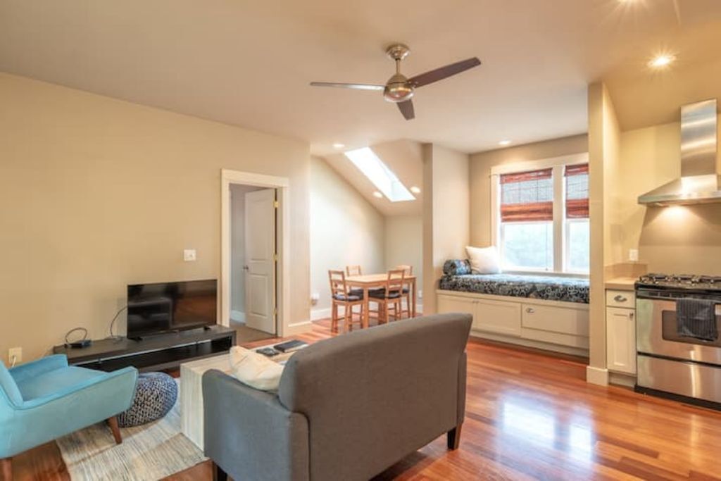 A modern apartment with a living room, dining area, kitchenette, and a ceiling fan.