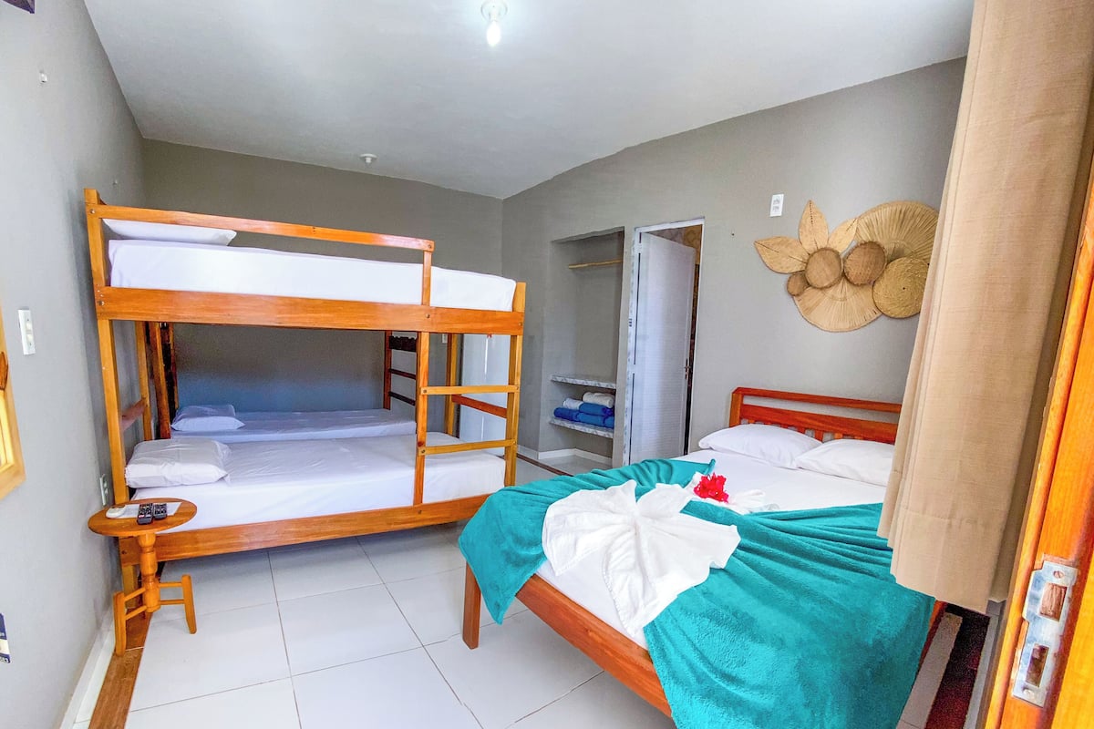 A room with bunk beds, a single bed, a small table, and a ceiling fan.