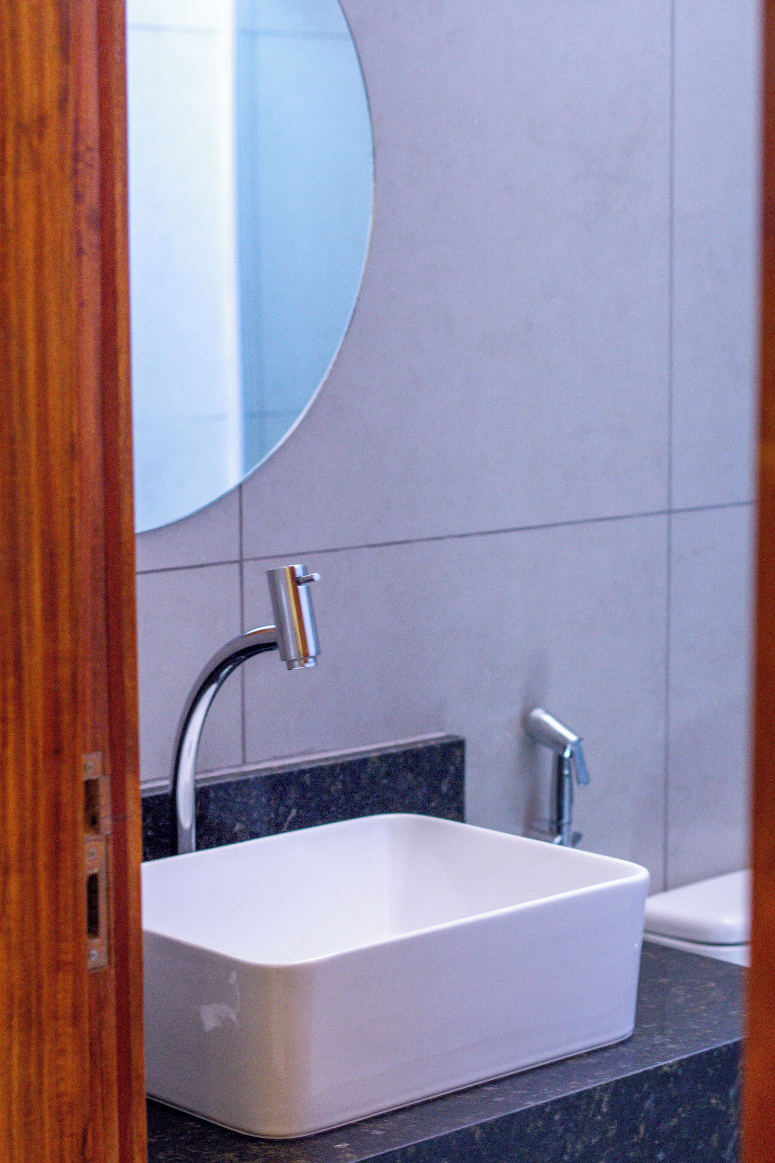 Un baño moderno con un lavamanos rectangular blanco, dos grifos y un espejo grande sobre el lavamanos.