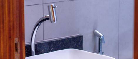 Un baño moderno con un lavamanos rectangular blanco, dos grifos y un espejo grande sobre el lavamanos.