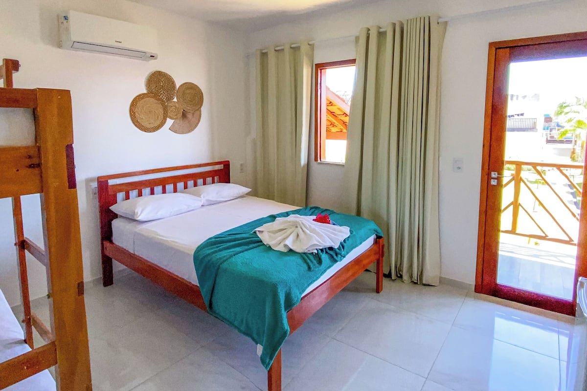 A single-bed room with a wooden frame, white bedding, a teal blanket, and a wooden ladder.