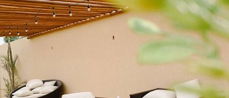 An outdoor seating area with wicker furniture and a bamboo ceiling.