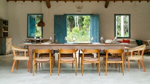 Un comedor con una larga mesa de madera, seis sillas y dos ventiladores de techo.