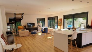 Un soggiorno moderno e open space con cucina, pavimento in legno e ampie finestre.