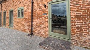 Een bakstenen gebouw met een groene deur, een raam en een naambordje.