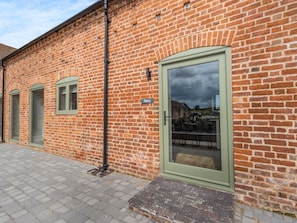 Een bakstenen gebouw met een groene deur, een raam en een naambordje.