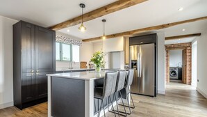 Een moderne keuken met een centraal eiland, donkere kasten en een houten plafond.