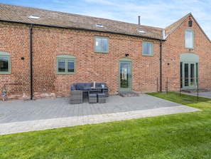 A brick building with a patio area, outdoor seating, and a green door.