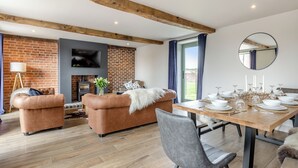 Een moderne woonkamer met een open haard, een gedekte eettafel en een grote spiegel aan de muur.