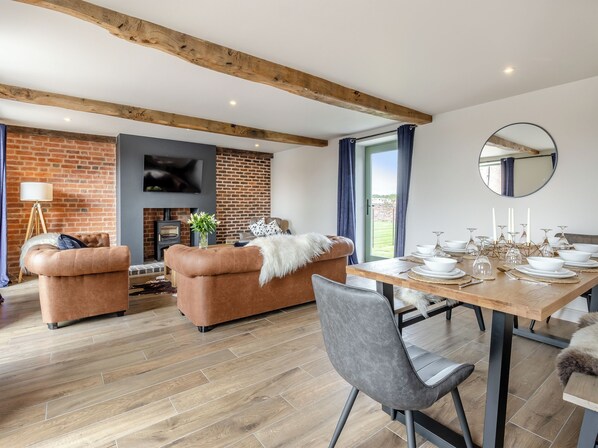 A modern living room with a fireplace, a dining table set for a meal, and a large mirror on the wall.