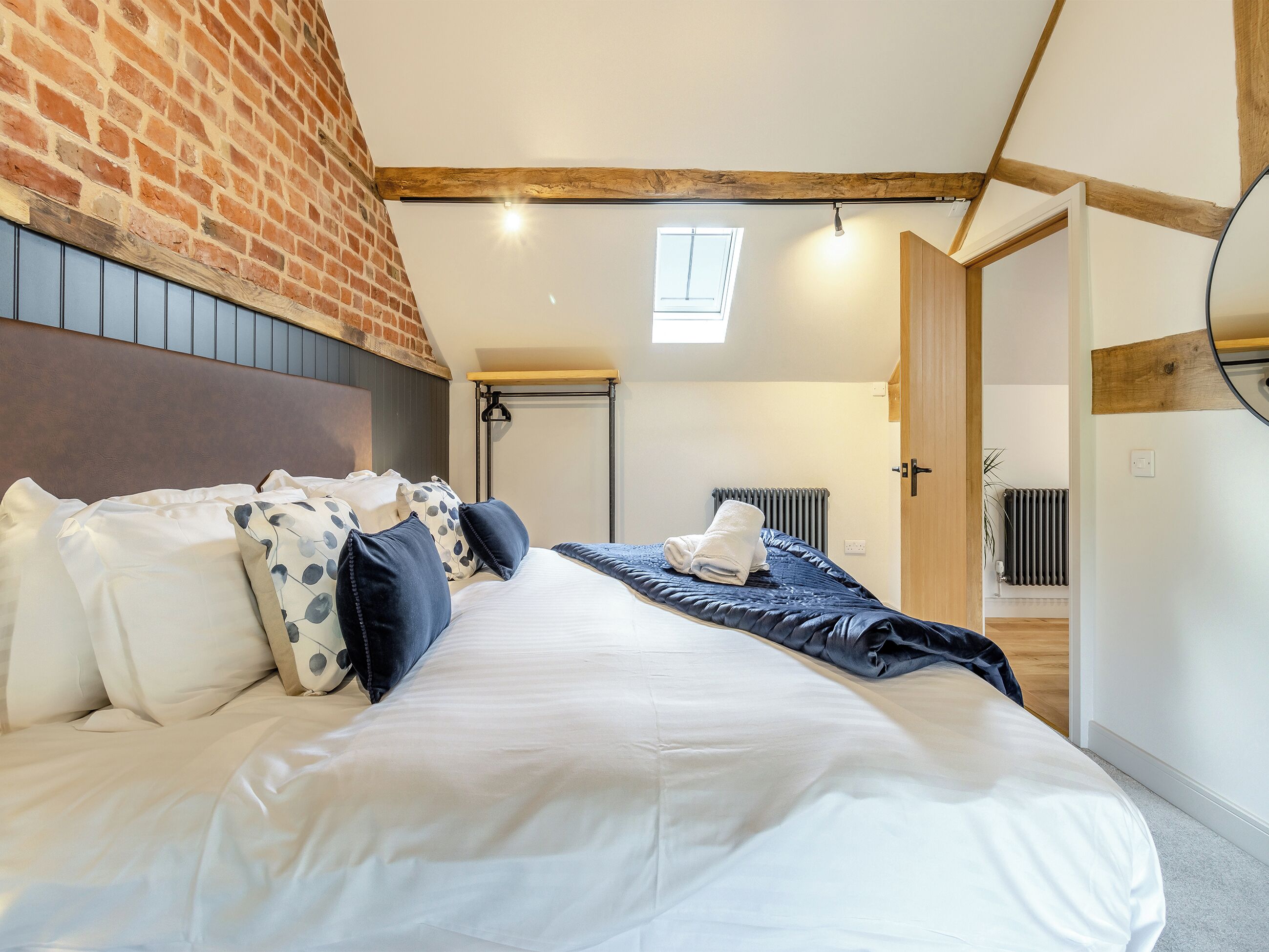 Une chambre à coucher avec un lit, un mur en briques, un puits de lumière, un radiateur et une porte en bois.