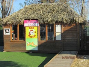 Un bâtiment en bois avec un toit de chaume, identifié comme un club pour enfants.