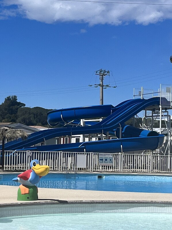 Un parc aquatique doté d’une grande piscine, de deux toboggans bleus et d’une statue représentant sa mascotte.