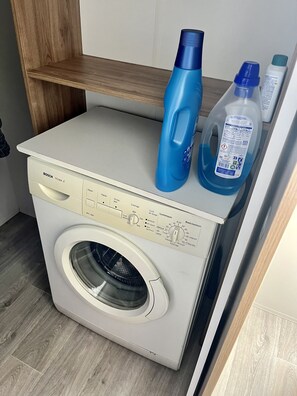 Une machine à laver Bosch blanche et compacte, dotée d’un panneau de commande et d’une porte transparente.