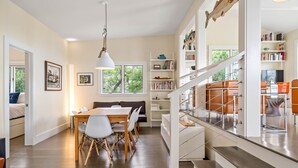 Een ruime woonkamer met een eettafel, stoelen, een bank en een trap met leuning.