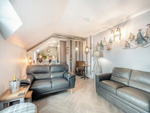 Un loft moderno con comedor, dos sofás de cuero, una mesa de centro, una lámpara de pie y un aplique de pared.