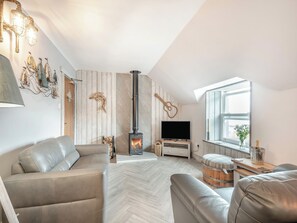 Ein modernes Wohnzimmer mit Kamin, einer Couch, einem Fernseher und einem Fenster mit Blick.