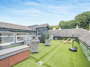 Ein Garten mit Rasenfläche, Gartenmöbeln und einem Tennisplatz.