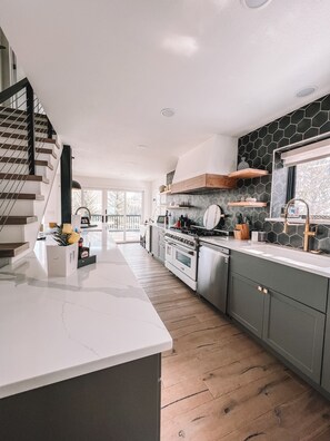 A modern kitchen with a central island, built-in oven, and a large window.