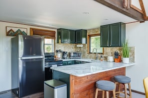 Een moderne keuken met een groot eiland, roestvrijstalen apparatuur en houten details.