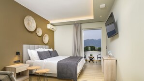 A modern hotel room with a bed, bedside tables, a desk, and a TV. - Nicolas Grand Suites - Adults Only (Kos)