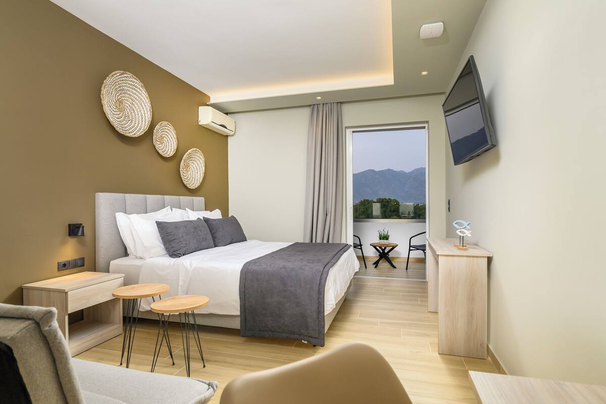 A modern hotel room with a bed, bedside tables, a desk, and a TV.