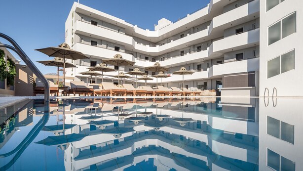 A modern hotel with a pool, multiple balconies, and sun loungers. - Nicolas Grand Suites - Adults Only (Kos)