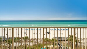 A beach view with a wooden railing, beach umbrellas, and a lifeguard tower. - Gulf Crest Gulf-Front Condo | Beach Chairs Included | Sleeps 8 (Panama City Beach)