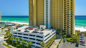 A multi-story hotel with a central tower, a parking garage, and a beach view. - Gulf Crest Gulf-Front Condo | Beach Chairs Included | Sleeps 8 (Panama City Beach)