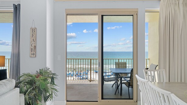 A balcony with a view of the beach, a table, chairs, and a potted plant. - Gulf Crest Gulf-Front Condo | Beach Chairs Included | Sleeps 8 (Panama City Beach)