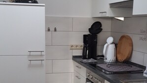 Cozinha moderna com armários brancos, bancada preta e diversos eletrodomésticos.