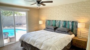 A bedroom with a large bed, a ceiling fan, a nightstand, and a view of a swimming pool. - Desert Oasis w/Pool & Spa Close to Saguaro National Park (Tucson)