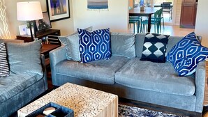 A living room with a grey sofa, two wooden coffee tables, a patterned rug, and a dining area visible through an open door. - Desert Oasis w/Pool & Spa Close to Saguaro National Park (Tucson)