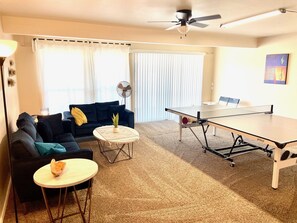 Uma sala de estar com sofá, mesa de centro e mesa de pingue-pongue.