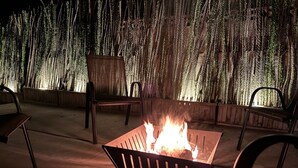 A fire pit in the center with chairs around it, set against a backdrop of vertical wooden slats. - Desert Oasis w/Pool & Spa Close to Saguaro National Park (Tucson)