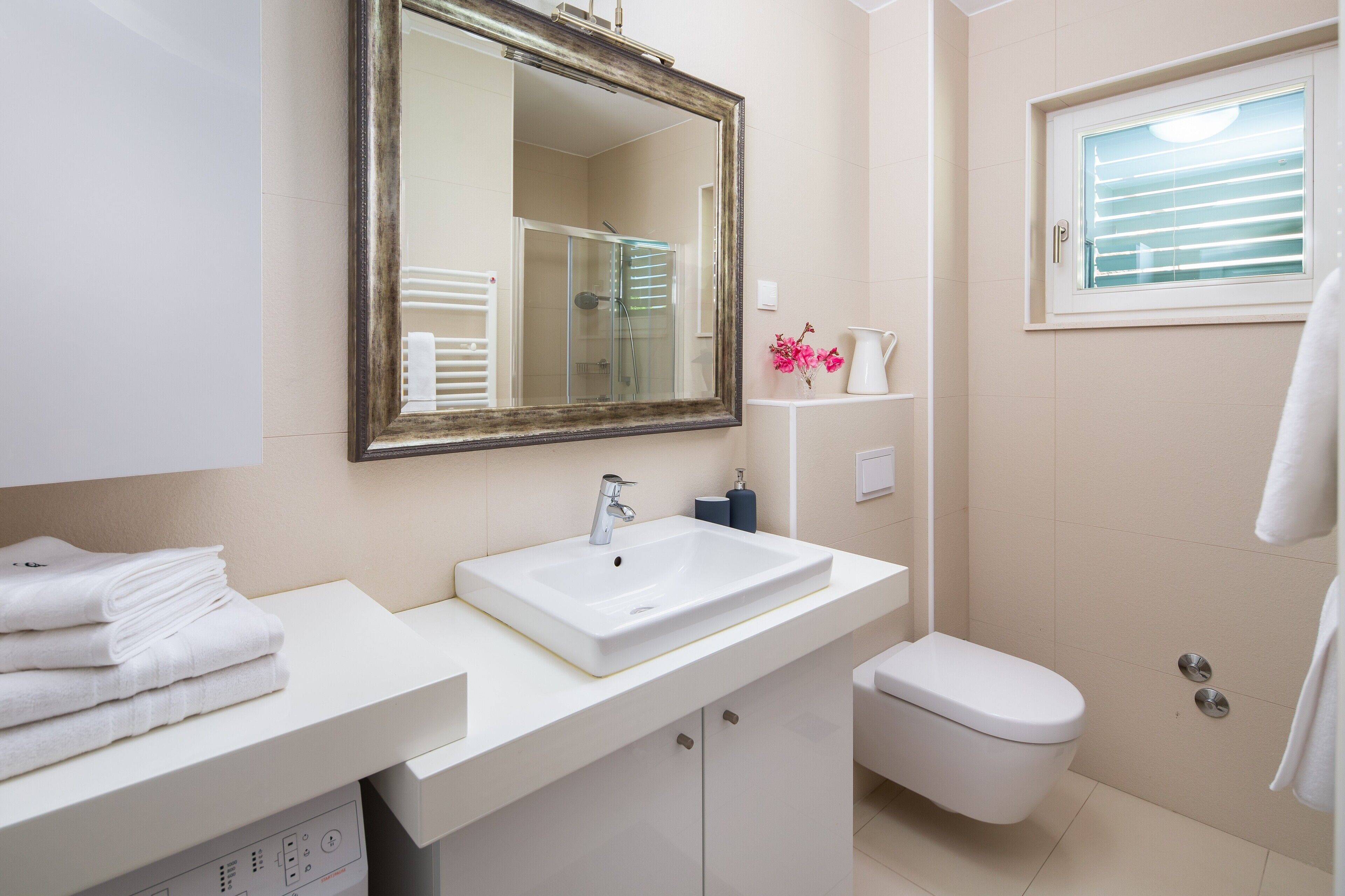 A bathroom with a white sink, a mirror, a toilet, and a shower.