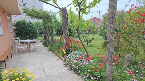 Een tuin met terras, zitplaatsen buiten en diverse planten.