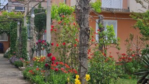 Een tuin met verschillende planten en bloemen, een pad en een gebouw met een balkon.