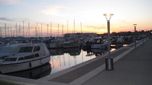 Een jachthaven met boten afgemeerd langs een waterkantpromenade.