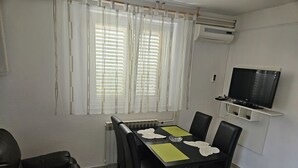 Een eetruimte met een tafel, stoelen, een televisie en een airconditioning.