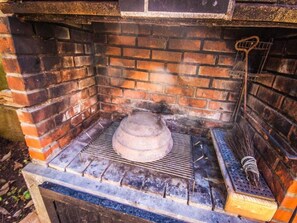 Un four en briques avec une marmite à l’intérieur, un gril et un balai.