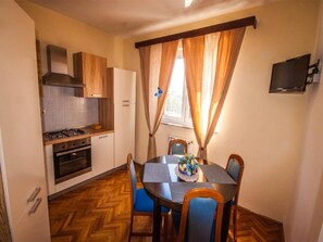 Una cocina compacta con estufa, horno y una mesa de comedor con sillas.