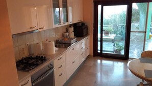 Een keuken met witte kastjes, een gasfornuis en een eethoek met een tafel en stoelen.