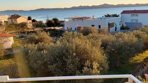 Un quartier résidentiel situé sur la côte, avec des maisons, une vue dégagée sur la mer et une chaîne de montagnes à l’horizon.